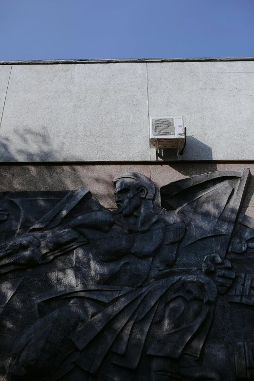 a statue that is on the side of a building, unsplash, socialist realism, air conditioner, low quality photo, panel of black, azamat khairov