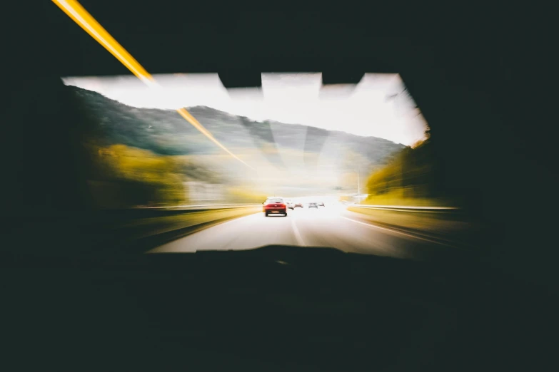 a car driving down a road with mountains in the background, by Thomas Häfner, unsplash, visual art, light entering through a blind, overexposed flash, multi-dimensional, high traffic