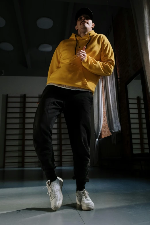 a man in a yellow jacket doing a trick on a skateboard, inspired by Ma Quan, trending on pexels, hyperrealism, standing in a dimly lit room, wearing a hoodie and sweatpants, full body cgsociety, she is dancing. realistic