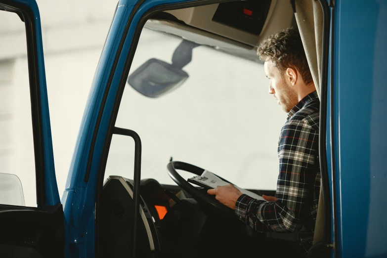 a man sitting in the driver's seat of a blue truck, pexels, renaissance, square, australian, reading, standing sideways