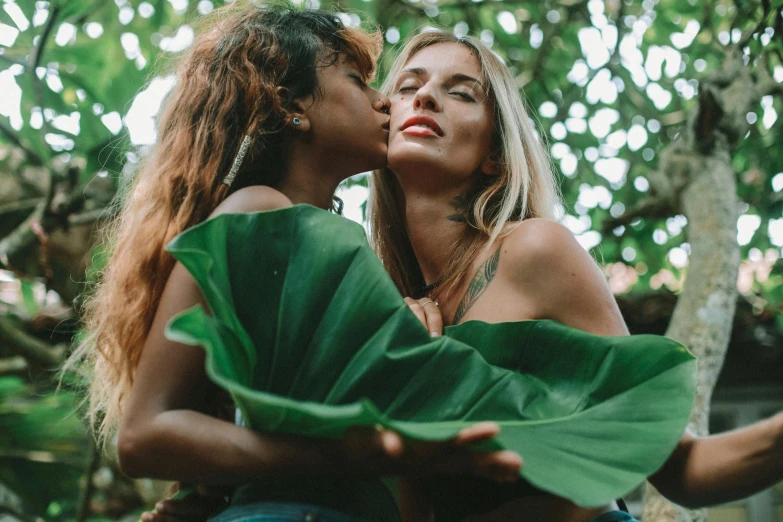 a couple of women standing next to each other, trending on pexels, big leaf bra, lesbian kiss, exotic flora, center of image