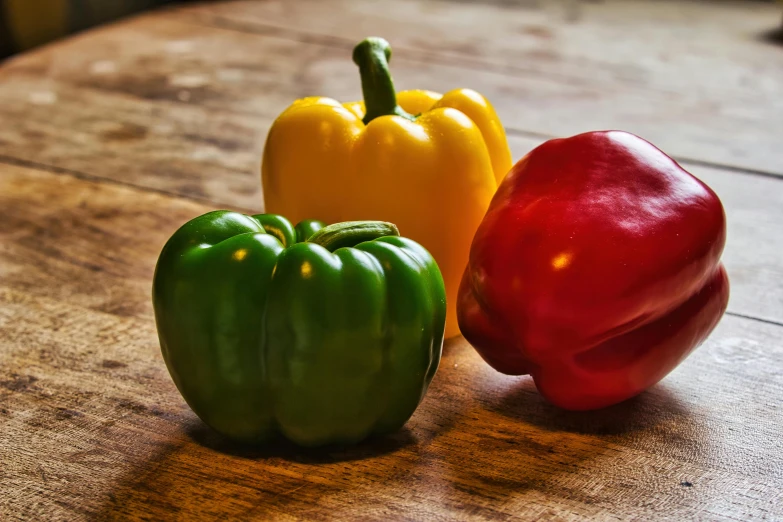 three peppers sitting on top of a wooden table, inspired by Albert Joseph Pénot, unsplash, renaissance, fan favorite, various colors, 1940s food photography, slightly round chin