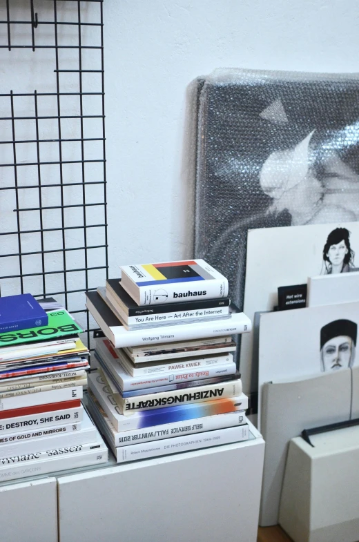 a stack of books sitting on top of a wooden floor, an album cover, by artist, unsplash, analytical art, rei kawakubo artwork, shelves, splash image, on a white table