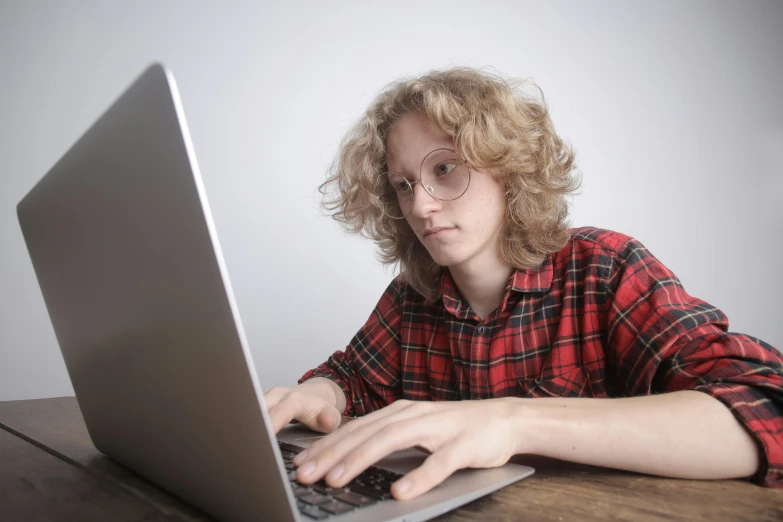 a young man sitting in front of a laptop computer, computer graphics, by Carey Morris, pexels, long hair and red shirt, aged 13, non-binary, lumberjack