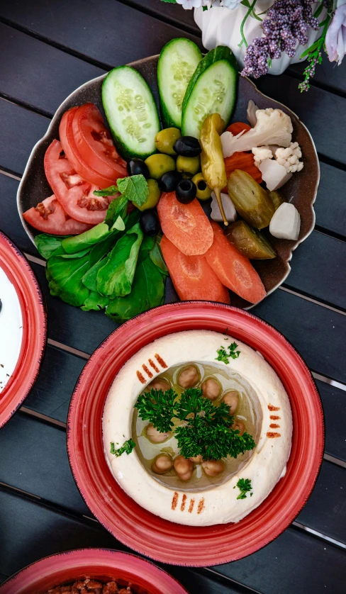 a table topped with plates of food on top of a wooden table, dau-al-set, green and red plants, thumbnail, humus, round-cropped