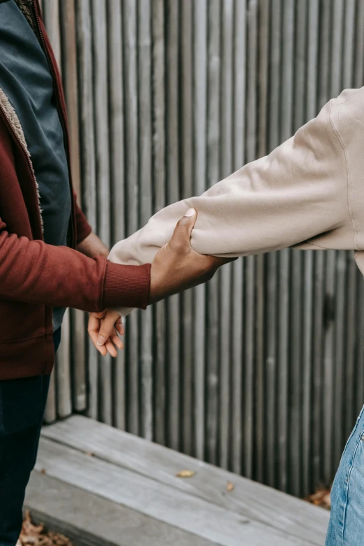 a couple holding hands while standing in front of a fence