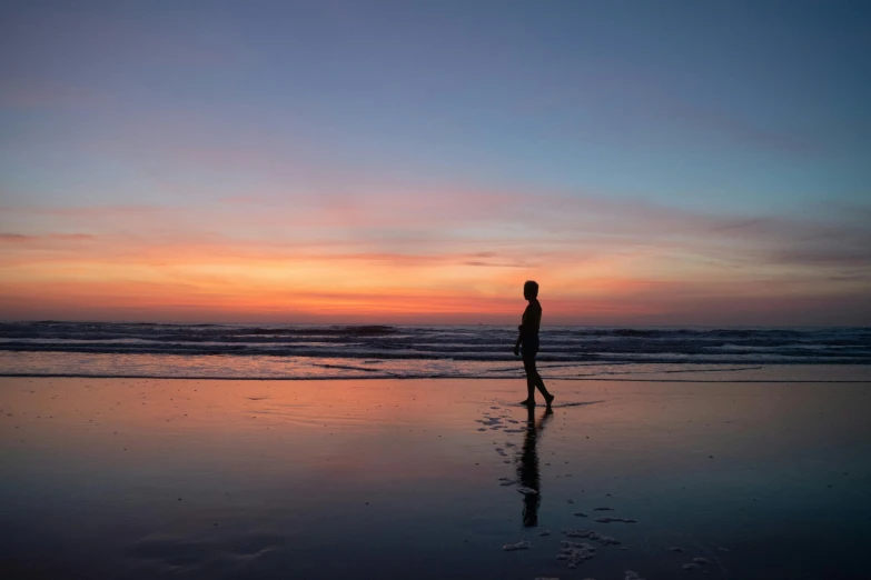 a person walking on top of a beach near the ocean