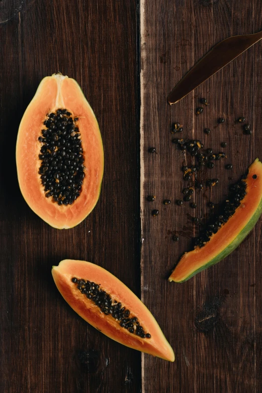 a couple of papanas sitting on top of a wooden table, black and orange, coral, fresh fruit, opening shot