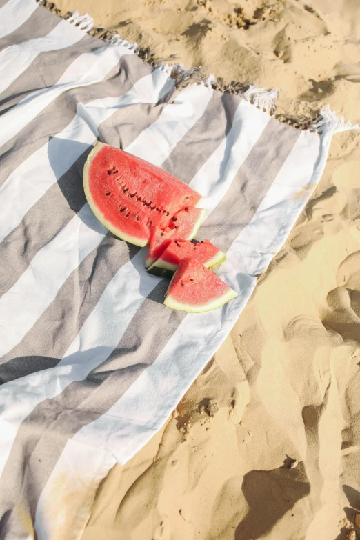 a slice of watermelon laying on a beach towel, by Niko Henrichon, trending on unsplash, happening, grey, sand, striped, swimsuit