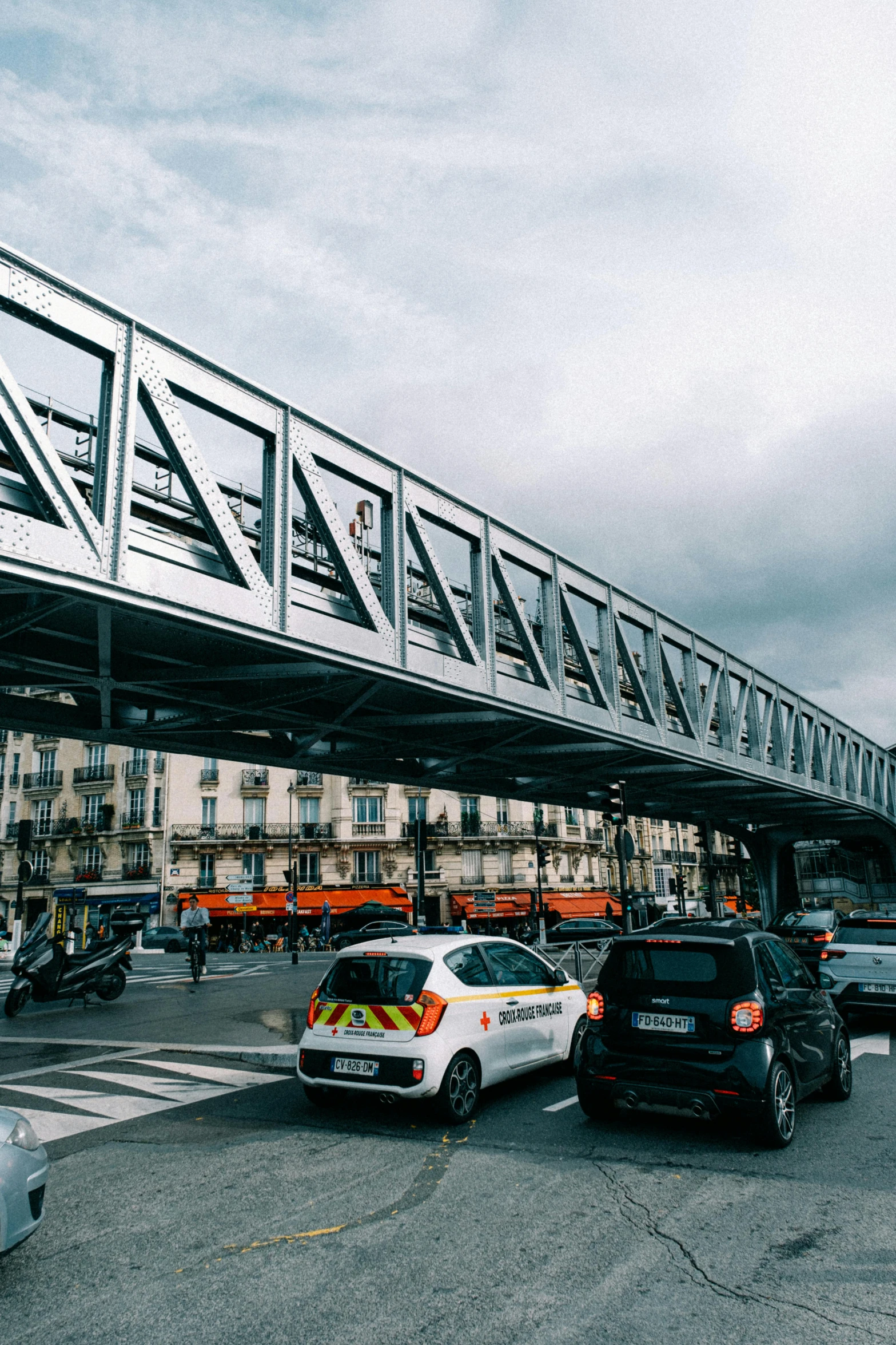 a pedestrian bridge over a busy city street, by Raphaël Collin, unsplash, paris school, cars parked underneath, square, 🚿🗝📝, construction