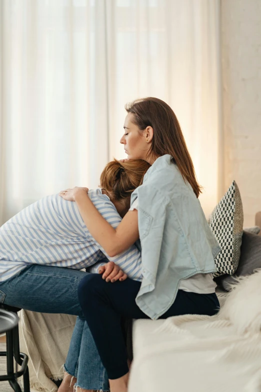 a couple of women sitting on top of a bed, grieving, arm around her neck, sitting on the couch, lgbtq