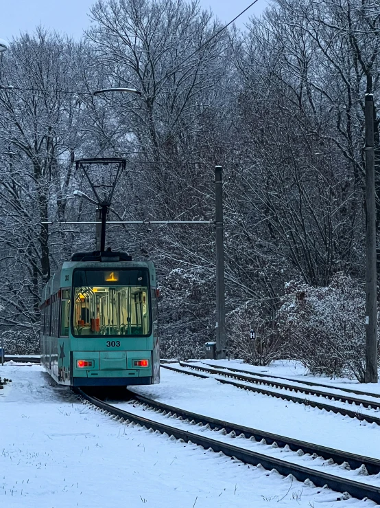 a blue train moving through the snow covered field