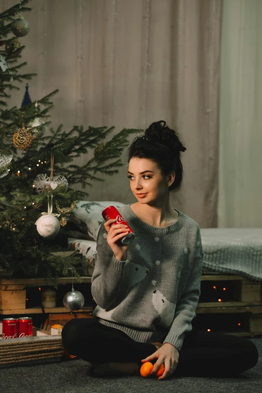 a woman sits next to a christmas tree and takes pictures