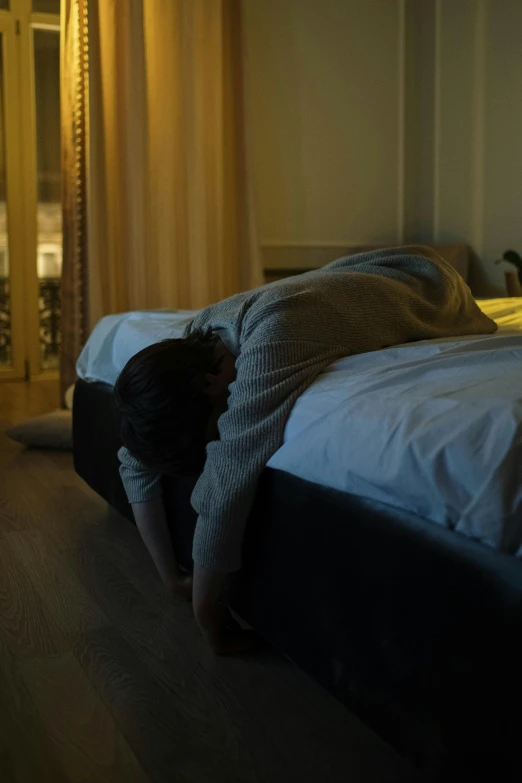 a person leaning over a bed in a dimly lit room