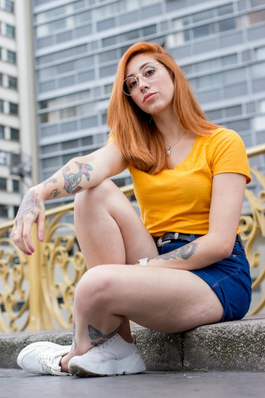 a woman with red hair sitting on a ledge, a portrait, by Sven Erixson, pexels contest winner, wearing a modern yellow tshirt, tattoos, promotional image, round thighs