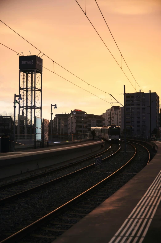 a train traveling down train tracks next to tall buildings, unsplash, sun at dawn, photo of zurich, taken in the late 2000s, helsinki