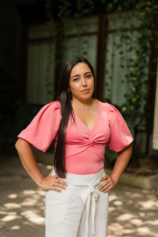 a woman in a pink top and white pants, a portrait, inspired by Gina Pellón, pexels contest winner, latinas, serious look, square, puff sleeves