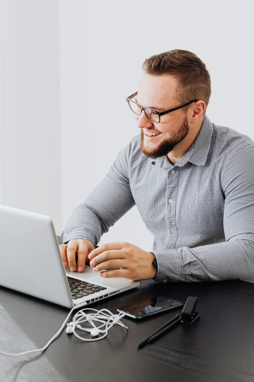 a man sitting at a table working on a laptop, trending on pexels, on grey background, slight nerdy smile, technical, nerds