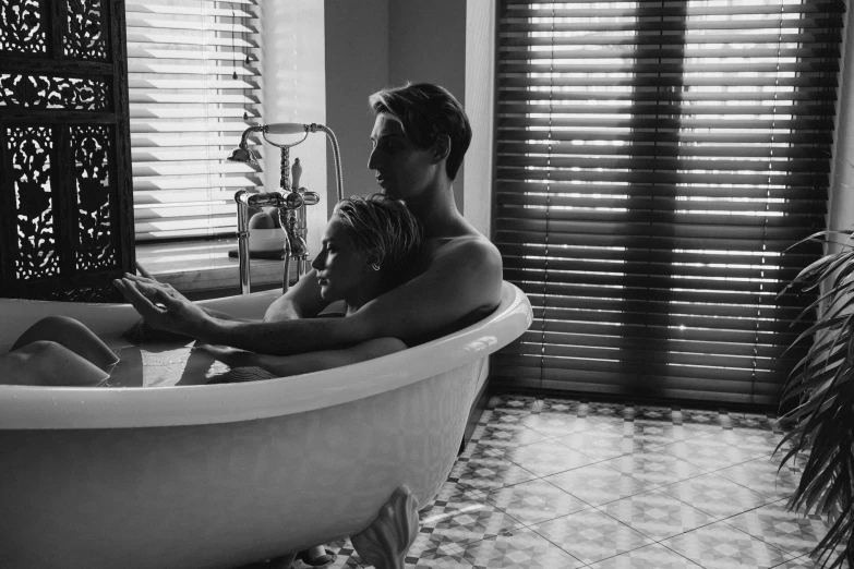 a black and white po of two people in the bathtub