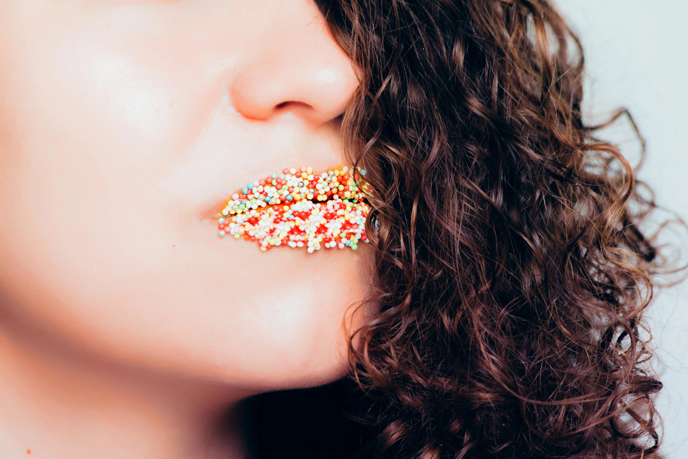 a close up of a person with a donut in their mouth, inspired by Elsa Bleda, trending on pexels, pointillism, long brown puffy curly hair, candies, lip scar, lesbian kiss