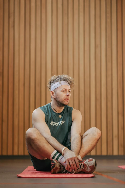 a young man sitting on a mat in a gym