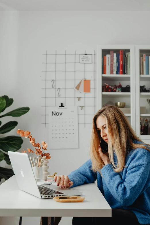 a woman sitting at a desk working on a laptop, trending on pexels, happening, seasonal, low quality photo, - 9, scandinavian