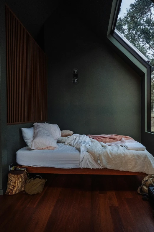 bed set in corner of dark room with windows