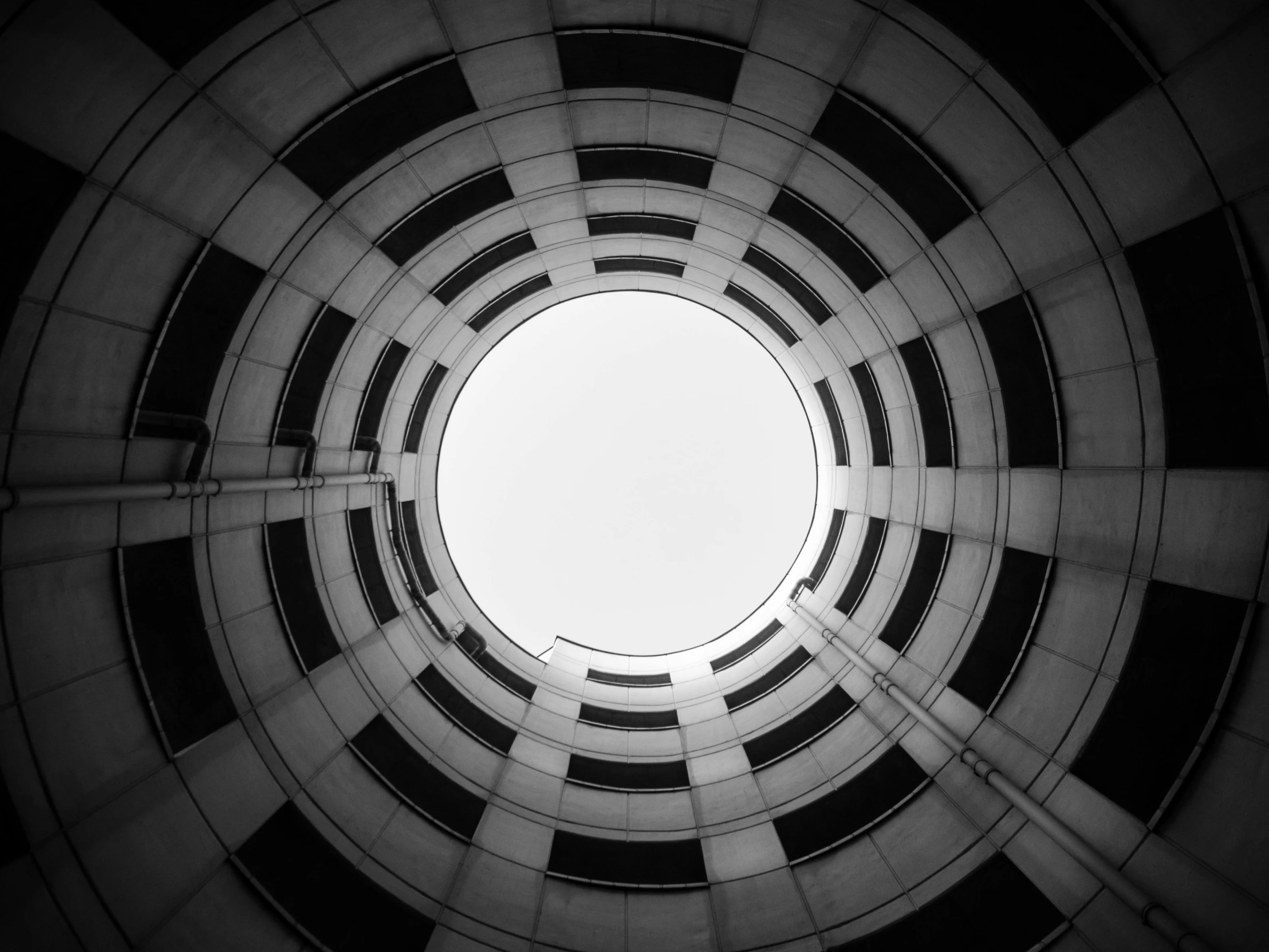 a black and white photo of a circular building, inspired by Alexander Rodchenko, unsplash, worm hole, looking upwards, white pale concrete city, unsplash photo contest winner