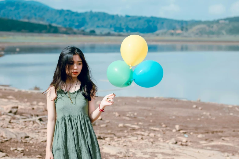 a woman in a green dress holding a bunch of balloons, pexels contest winner, korean girl, at the waterside, indian girl with brown skin, 15081959 21121991 01012000 4k