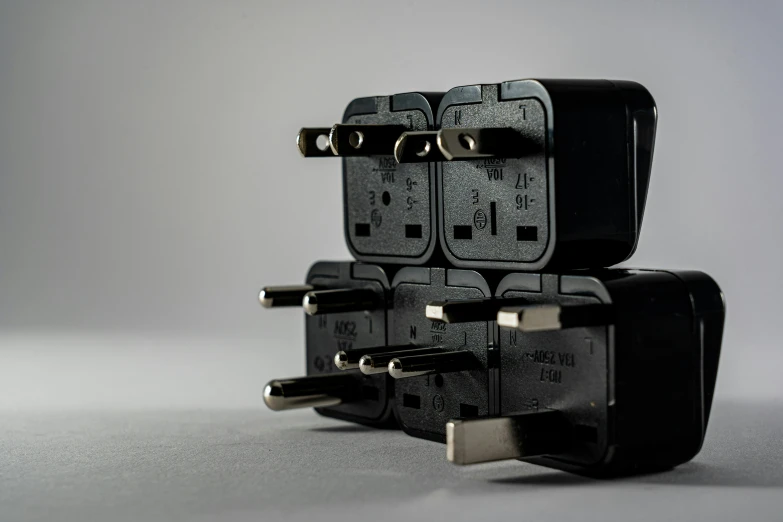 a couple of plugs sitting on top of each other, by Bernardino Mei, unsplash, dau-al-set, square, black plastic, several continents, electrical details