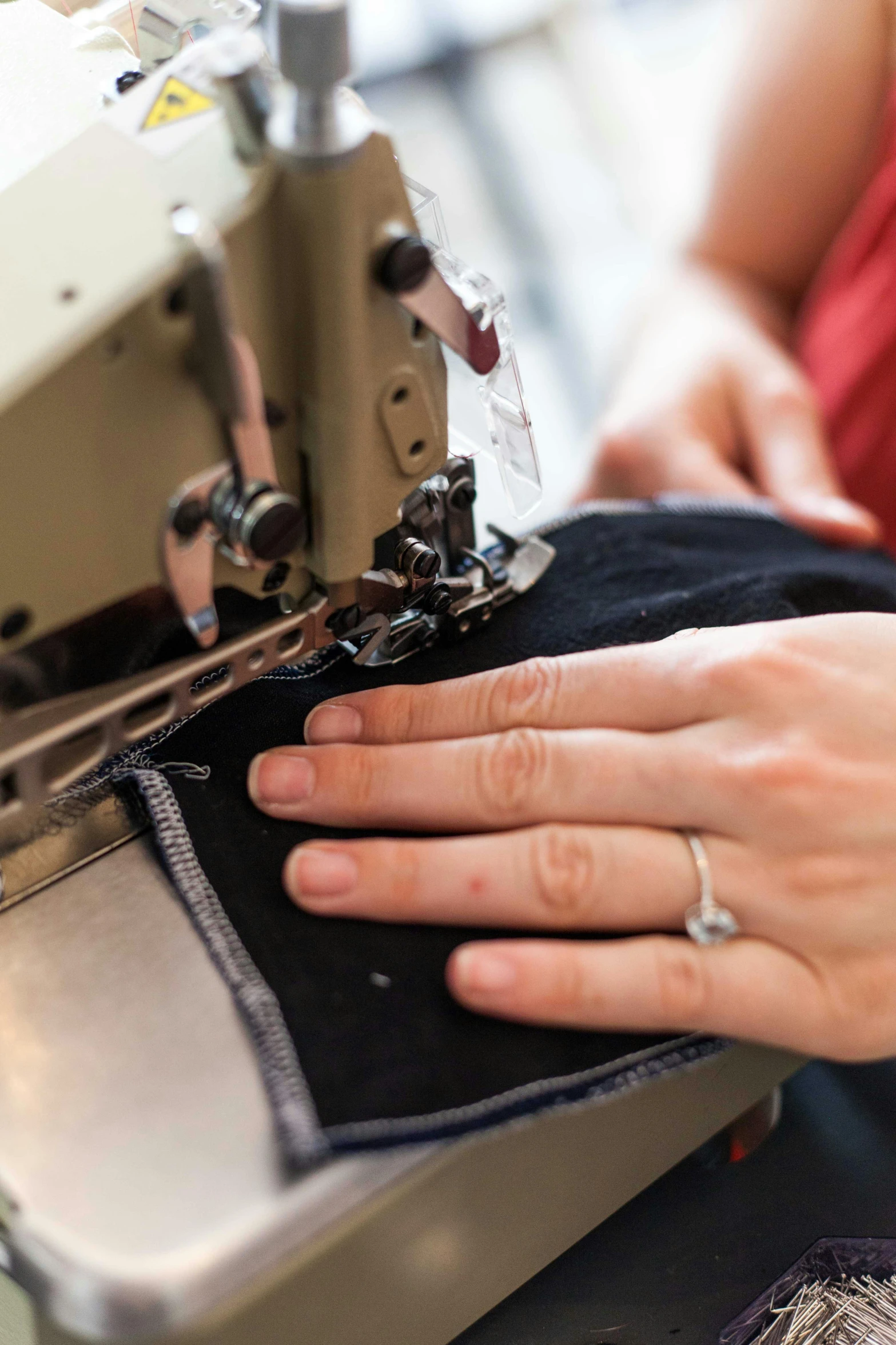 a close up of a person using a sewing machine, cloth and metal, centred, raising an arm, digital image