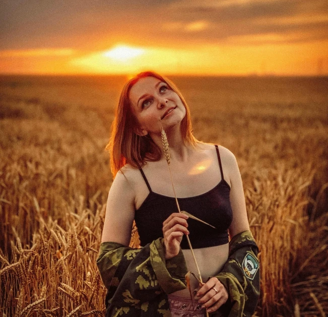 woman wearing gloves standing in a wheat field at sunset