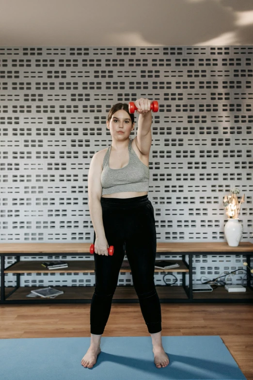 a woman standing with dumbbells in a gym