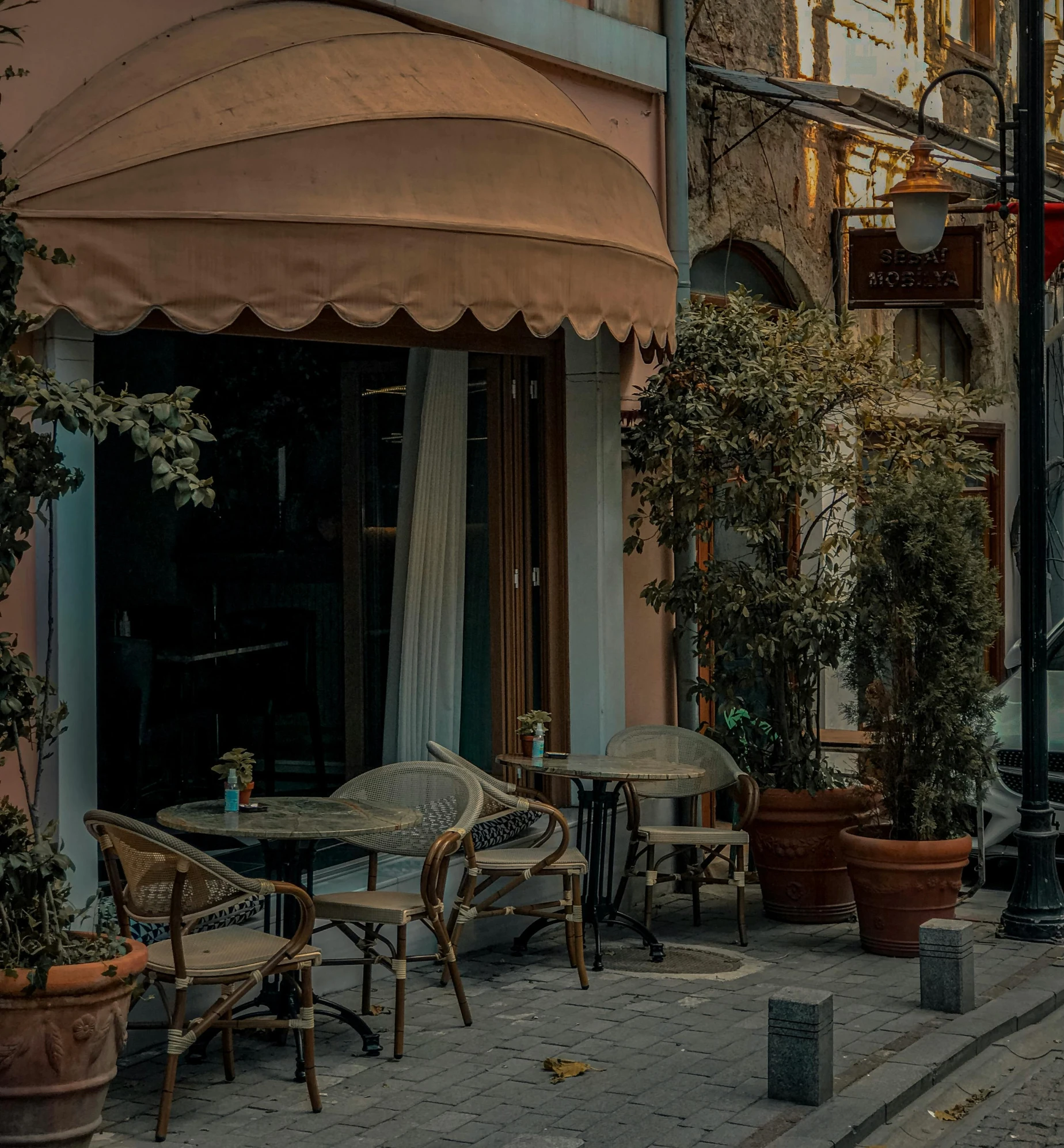 a table and chairs outside of a cafe with a large umbrella over it