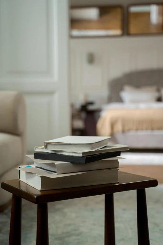 a stack of books sitting on top of a wooden table, inspired by Alexander Roslin, neoclassicism, hotel room, brown