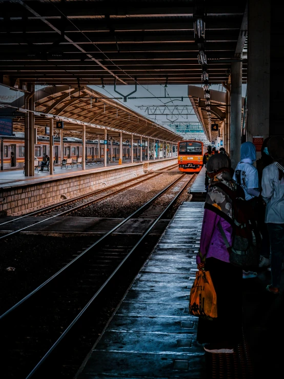 people waiting on a train platform for the light to change