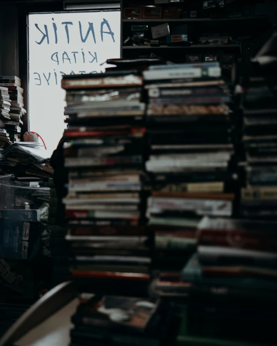 a room filled with lots of books next to a window, an album cover, trending on unsplash, lots of signs, portait photo, piles of books, thumbnail