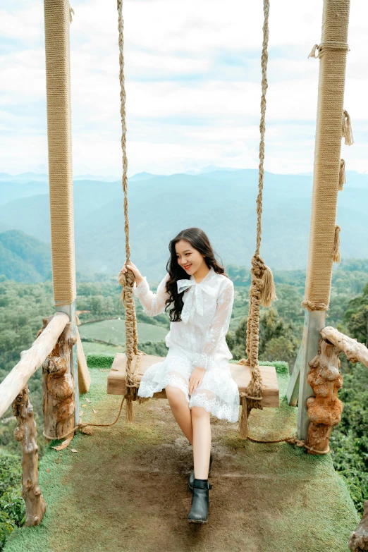 a woman in a white dress sitting on a swing, pexels contest winner, sumatraism, sitting cutely on a mountain, mai anh tran, at the terrace, actress