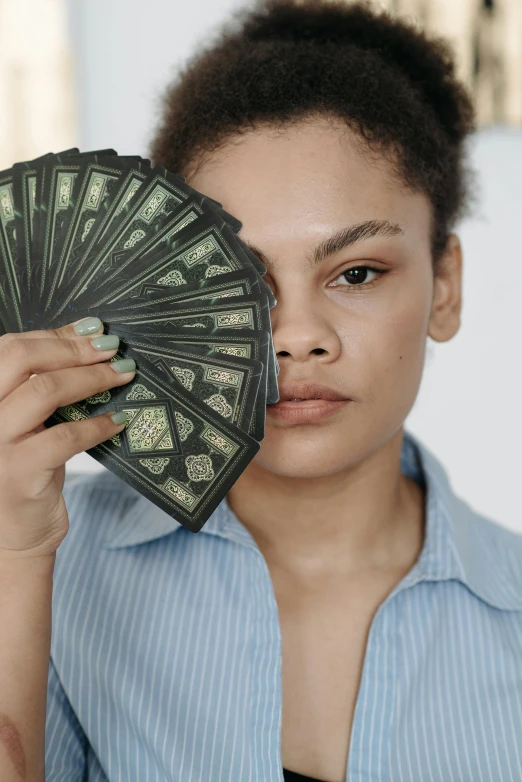 a woman holding a fan of money in front of her face, pexels contest winner, renaissance, black paper tarot, mixed race, magic: the gathering, slightly minimal