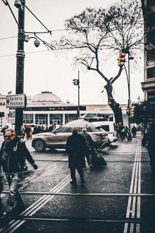 two people crossing a street while wearing coats