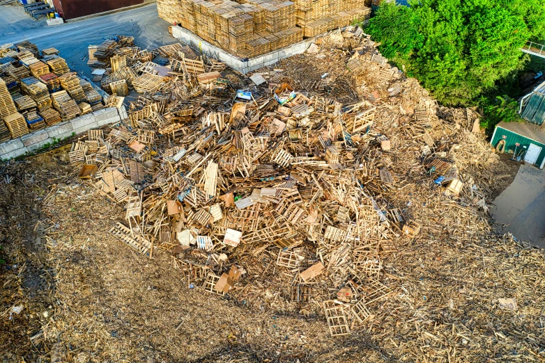 a pile of wood sitting on top of a pile of dirt, an album cover, unsplash, land art, drone photograpghy, piles of trash, hundreds of chairs and tables, 2 0 2 2 photo