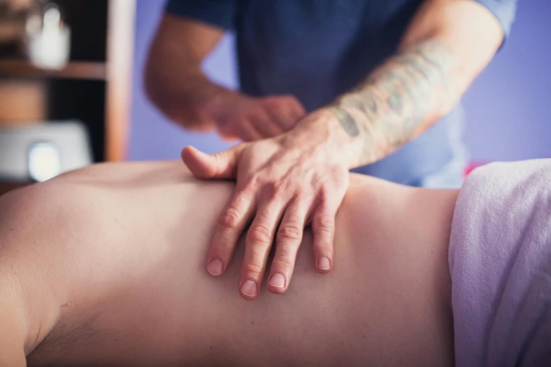 a man getting a back massage in a room, by Évariste Vital Luminais, unsplash, colourised, visible stomach, manuka, slightly blurred