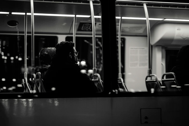 a black and white photo of people sitting on a bus, a black and white photo, by Niko Henrichon, pexels contest winner, realism, night in the city, silhouette of a man, inside the train, night time footage