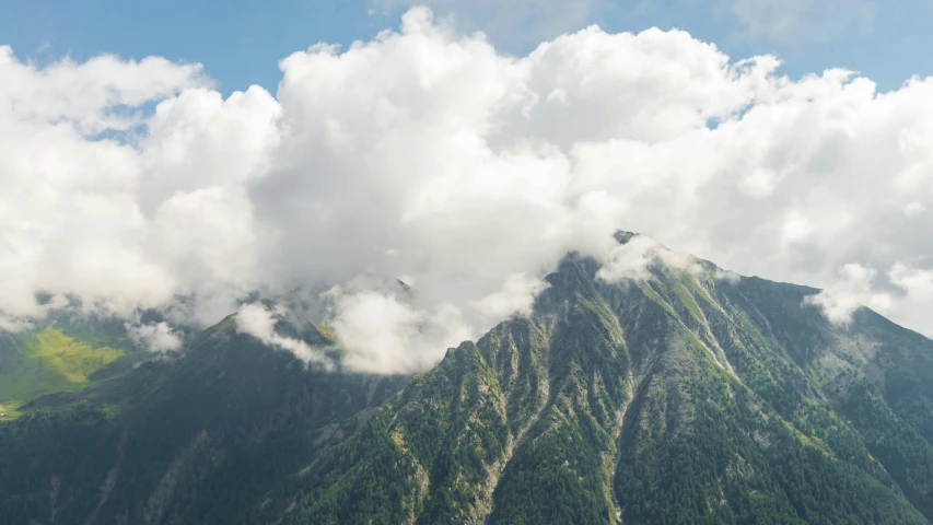 the tops of mountains with clouds and trees in them