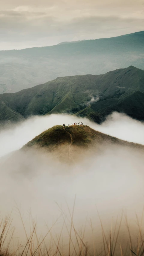 a view of the hills with people atop in fog