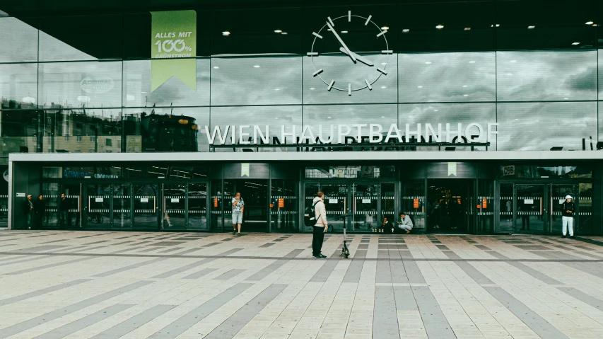 a couple of people that are standing in front of a building, by Thomas Häfner, pexels contest winner, train station, header text”, vereschagin, storefront