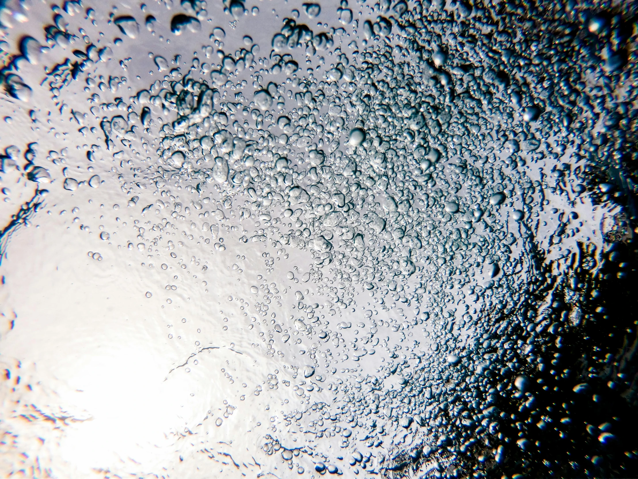 a close up of water droplets on a glass, inspired by Lucio Fontana, unsplash, auto-destructive art, volumetric light from below, looking towards camera, an eerie whirlpool, cellshaded