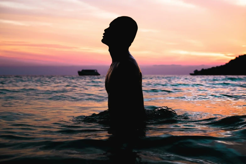 a man standing in the ocean at sunset, an album cover, pexels contest winner, man is with black skin, photography of kurzgesagt, outlined silhouettes, relaxing