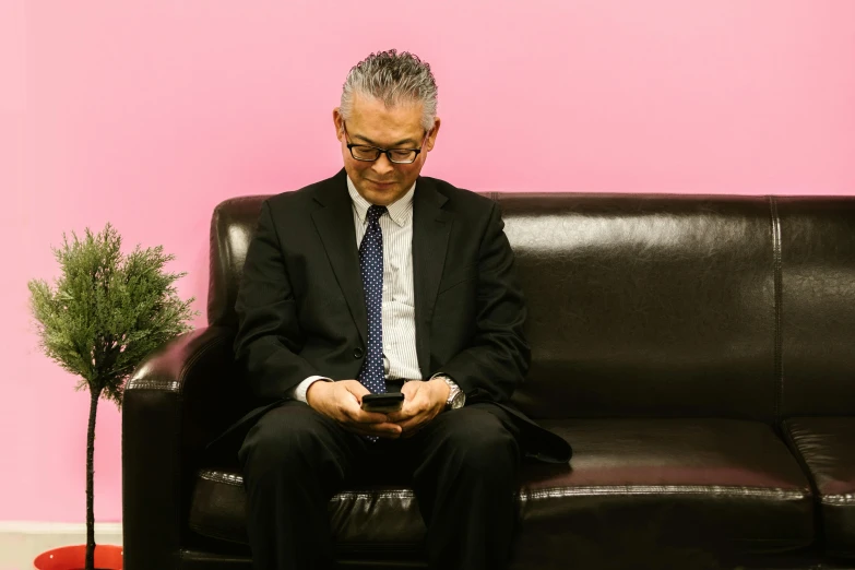 a man is sitting on a couch using his phone