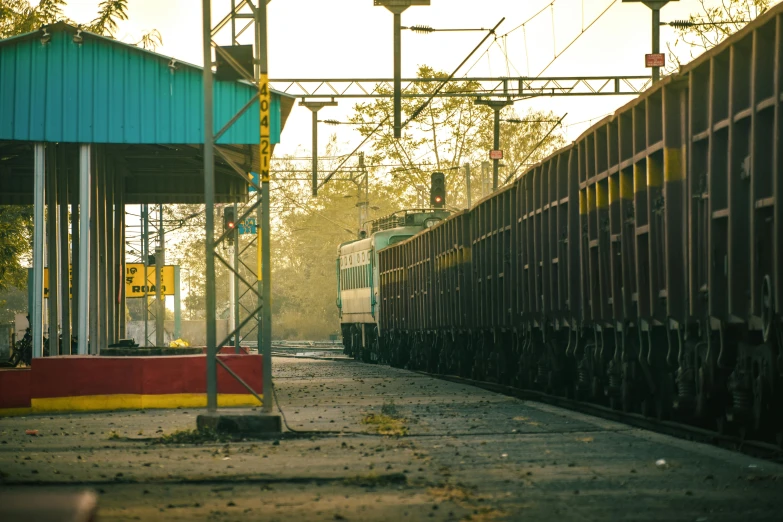 a train traveling down train tracks next to a train station, pexels contest winner, indore, thumbnail, industrial colours, sunny morning light